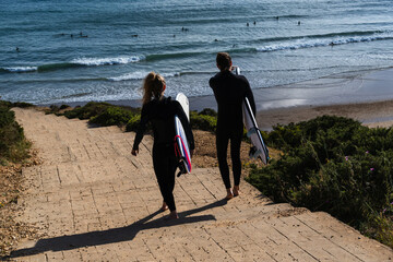 Surfers descending the steps of Praia do Beliche beach in Sagres, Algarve, Portugal. Sunny day with...
