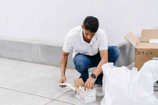 Focused man unpacking box on warehouse floor