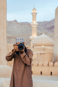 Arab photographer taking a photo with a mosque in the background