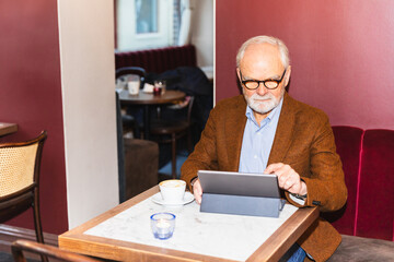 Senior man using tablet in cafeteria