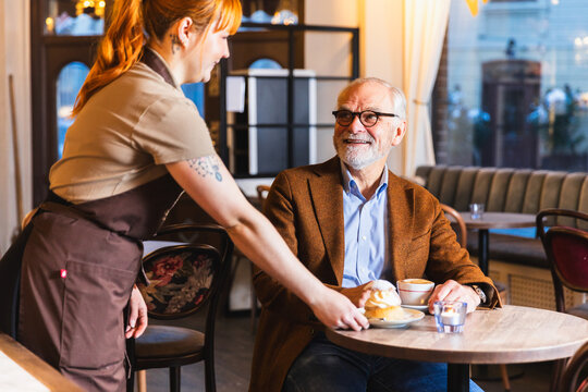 Waiter serving cake to happy costumer 