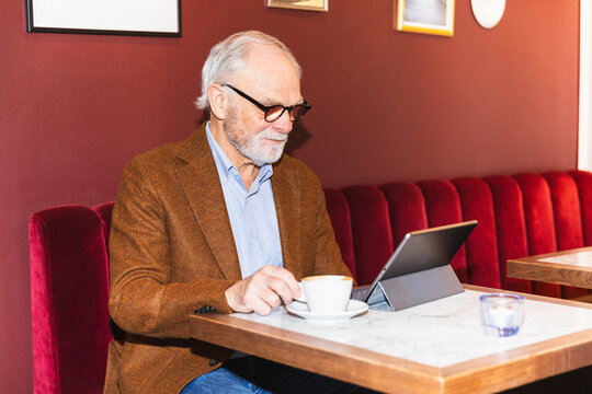 Senior man using tablet in cafeteria