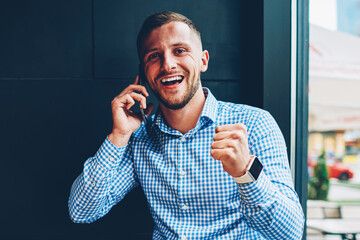 Excited male businesswoman overjoyed with good news during mobile phone conversation looking at camera,young startupers celebrating achieved success completing project together talking on cellular