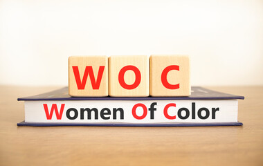 WOC women of color symbol. Concept words WOC women of color on beautiful wooden blocks and book....