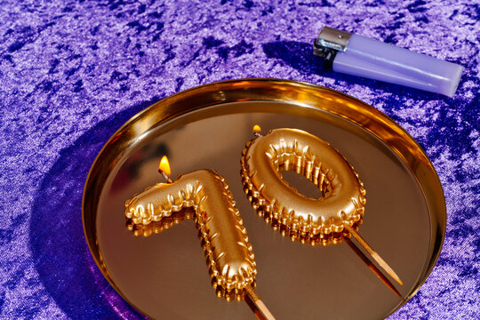 pair of lit golden candles forming the number 70