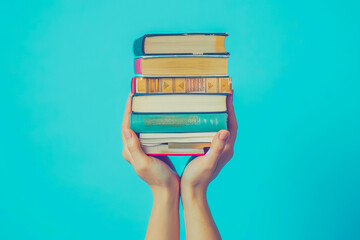 Women's hands hold a stack of books on a blue background. Concept education, study, library, science, hobby, knowledge, book exchange, leisure time