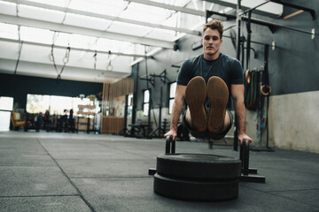 Determined sportsman doing L lift over poles on gym