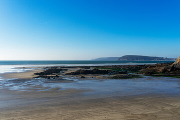 Plage de la presqu'île de Crozon, joyau breton baigné par la mer d'Iroise, avec sable fin, sillons rocheux, et ciel bleu.