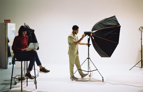 Photographer adjusting flashlight at studio