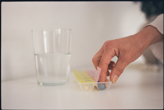 Woman taking pills and vitamins from pillbox