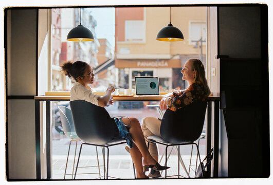Young colleagues discussing business during coffee break