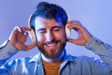 A man is smiling while wearing headphones. He appears happy and engaged with the music playing...