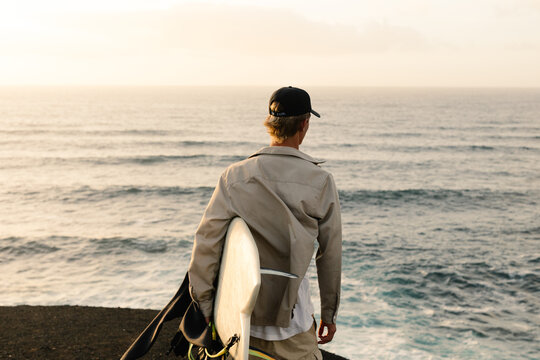 A young surfer marvels at the waves crashing against the shore