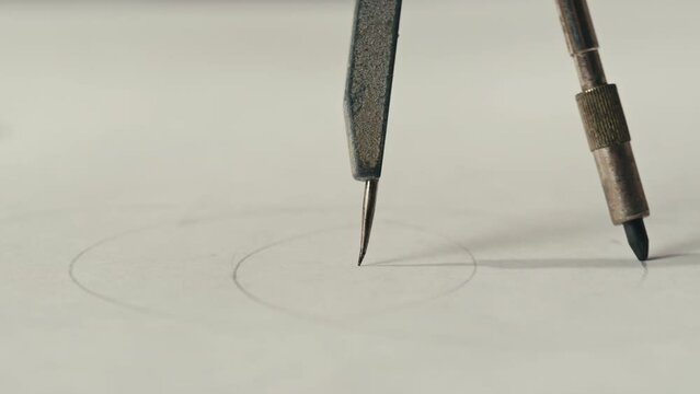 Close-up of compass drawing on white paper macro. Making some circle and measuring distance on white list by compass close-up. Drawing and sketching lessons concept.