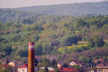 Komin huty, domy i zalesione góry - obrzeża Ostrowca w majowy poranek. Mglisty wiosenny poranek na obrzeżach Gór Świętokrzyskich na obrzeżach miasta. © Grzegorz