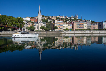 La Saône avec un bateau de croisière et vue sur l'église Saint-georges du vieux Lyon, la colline de Fourvière et les quais de Saône en été
