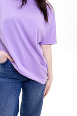 Woman in a long lilac T-shirt and blue jeans on white background
