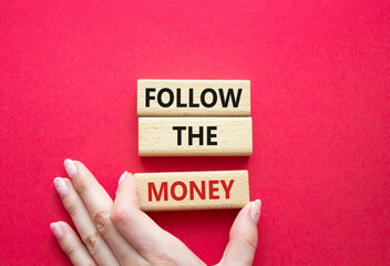 Follow the Money symbol. Concept word Follow the Money on wooden cubes. Businessman hand. Beautiful...