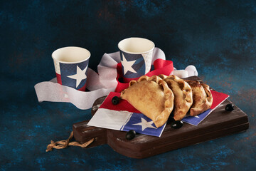 empanadas de pino junto a vasos con bandera de Chile, fondo celebración fiestas patrias de Chile
