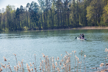 Obraz premium Beautiful scenery with lake, people in the distance paddling on a SUP. Enjoying the vacation. Landscape in the background.