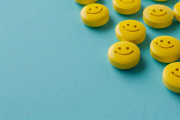 Bright yellow smiley face antidepressant pills scattered on a vibrant blue background, representing positivity and mental health care