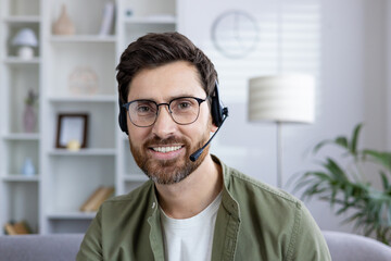Smiling man with headset engaged in a virtual meeting from his modern home office. Business and...