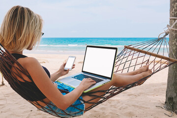 Female freelancer entrepreneur lying on hammock and doing remote business work at modern laptop...