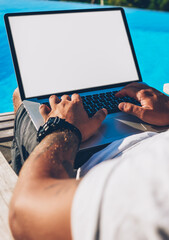 Cropped image of male hands typing text information on keyboard of modern laptop computer with...