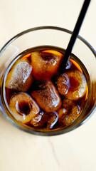 Cold brew coffee in glass cup on the table. Iced coffee with ice cube. Cold summer drink on a beige table