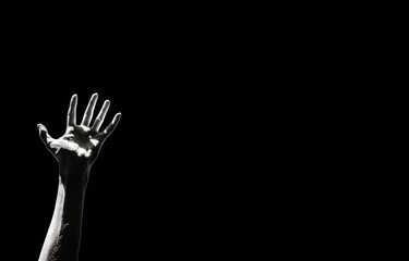 Hand reaching up in darkness. Black and white dramatic lighting. Emotional and expressive concept.