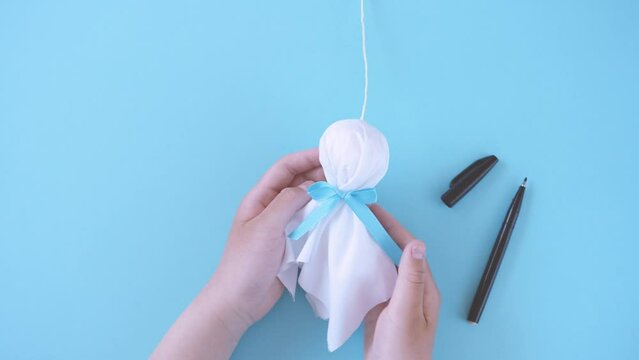 making a little handmade doll called a teru teru bozu to wish for good weather tomorrow. てるてる坊主を作る