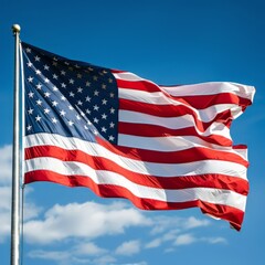 Waving American flag against a clear blue sky with a few clouds