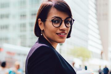 Half length portrait of happy businesswoman dressed in stylish formal wear and eyeglasses smiling...