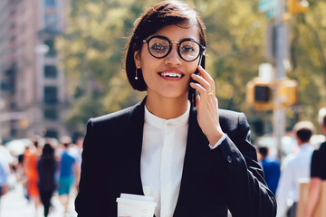 Portrait of elegant female entrepreneur talking on cellphone about business while passing crosswalk...