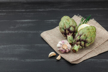 Fresh green artichokes cooking on wooden background. Traditional seasonal ingredients