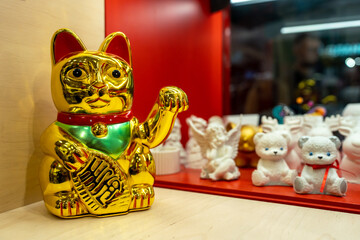 Maneki Neko, Japanese Lucky Cat in a gift shop window. Golden cat brings good luck and wealth...