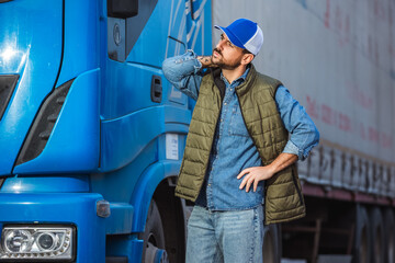 Tired male driver standing in front of his truck and streching out after a long drive