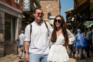 Young couple tourists walking in the ancient European city center. Explorers have trip to monument...