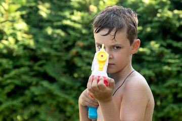 Funny boy with an amazing smile holding a water gun on the backyard	