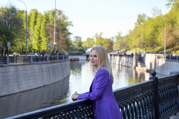 A girl walks along the embankment near the water in the city.