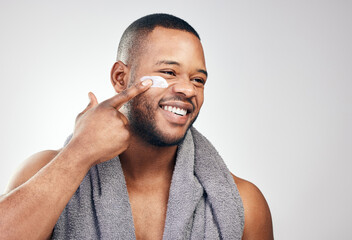 Black man, face cream and smile in studio for beauty with application, cosmetics and pride by...