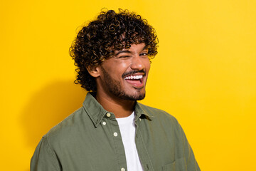 Fototapeta premium Portrait photo of young attractive hispanic guy in khaki shirt blinking eye and flirting with you isolated on yellow color background