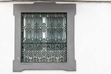 Green barred window in a concrete frame.