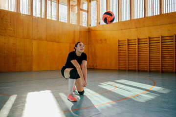 Woman volleyball player kneeling while receiving a ball with a bump