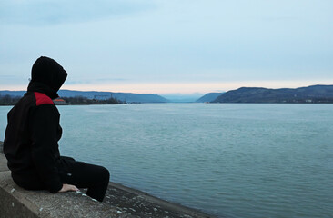Photo taken on the Danube with a boy sitting on a pier with his back to the camera