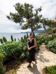 Beautiful young woman in a chic dress elegantly poses near the pool at a luxurious villa