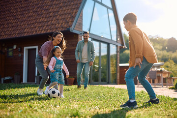 Carefree family having fun while playing with  ball in backyard.