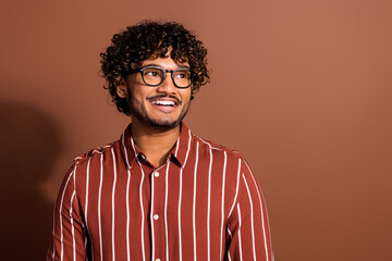 Fototapeta premium Photo of nice young man look empty space wear striped shirt isolated on brown color background