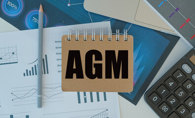 AGM text on notepad with office concept background. Business concept