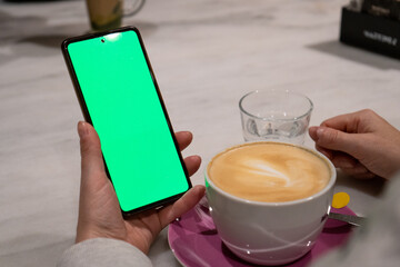 Mujer sosteniendo un teléfono móvil con la pantalla verde. Recurso gráfico para publicidades y...